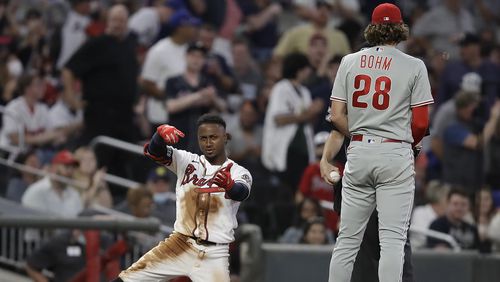 Ozzie Albies of the Braves celebrates beside Phillies third baseman Alec Bohm after hitting a triple in the fourth inning of a baseball game Saturday, May 8, 2021, in Atlanta.