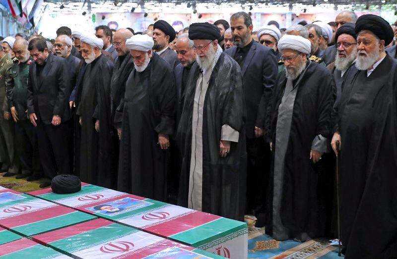In this photo released by the office of the Iranian supreme leader, Supreme Leader Ayatollah Ali Khamenei, center with black turban, leads a prayer over the flag-draped coffins of the late President Ebrahim Raisi and his companions who were killed in a helicopter crash on Sunday in a mountainous region of the country's northwest, at the Tehran University campus, during a funeral ceremony for them in Tehran, Iran, Wednesday, May 22, 2024. (Office of the Iranian Supreme Leader via AP)
