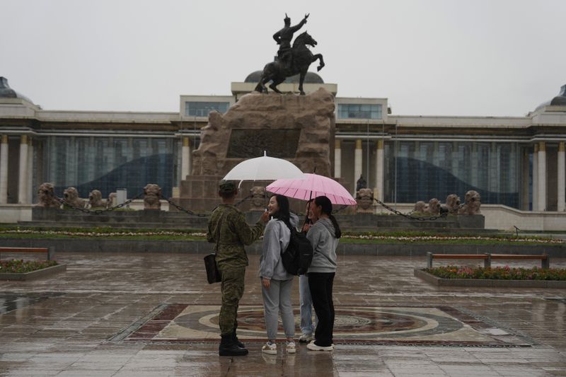 Young Mongolians chat under umbrellas as it rains on Sukhbaatar Square in Ulaanbaatar, Mongolia on Thursday, June 27, 2024. Mongolia, where parliamentary elections are being held Friday, is a sparsely populated and landlocked Asian nation known for its bitter winter cold and independent spirit. (AP Photo/Ng Han Guan)
