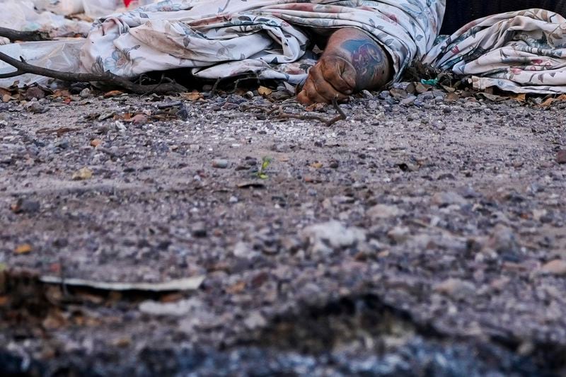 FILE - The dead body of a man, his arm marked with a tattoo of the Virgin of Guadalupe, lies covered on a street in La Costerita neighborhood of Culiacan, Sinaloa state, Mexico, Sept. 19, 2024. (AP Photo/Eduardo Verdugo, File)