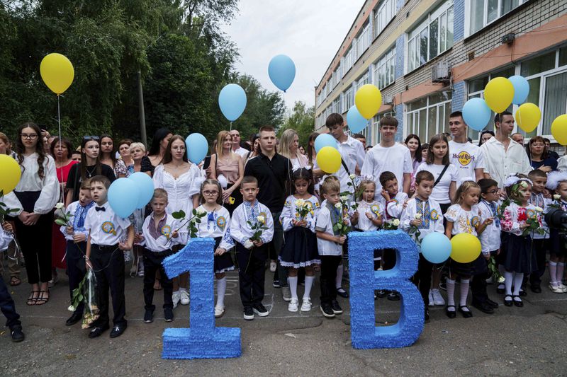 First-grades wait for the beginning of the traditional ceremony for the first day of school in Zaporizhzhia, Ukraine, Sunday Sept. 1, 2024. Zaporizhzhia schoolchildren celebrated the traditional first day of school near the frontline. With the front just 40 kilometers away, the war is never far from the minds of teachers and families. (AP Photo/Evgeniy Maloletka)