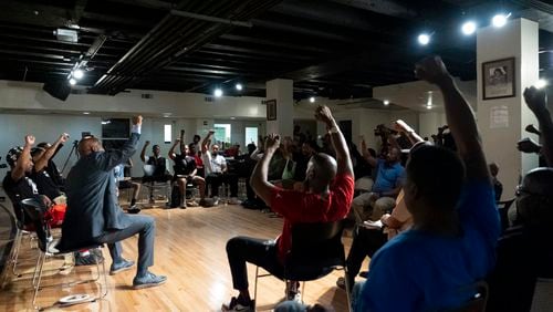 Panelists and attendees raise their fists during a Black Man Lab meeting to discuss the candidacy of Vice President Kamala Harris, Monday, July 22, 2024, in Atlanta. (AP Photo/Stephanie Scarbrough)