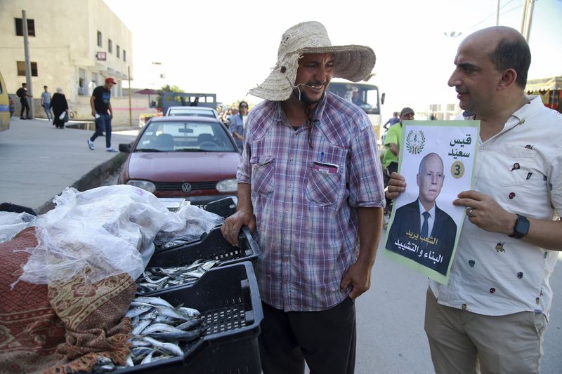 A supporter of Tunisian President and candidate for re-election Kais Saied meets with residents of a neighbourhood during a campaign tour, in Ariana, Tunisia, Thursday, Sept. 26, 2024. (AP Photo/Anis Mili)