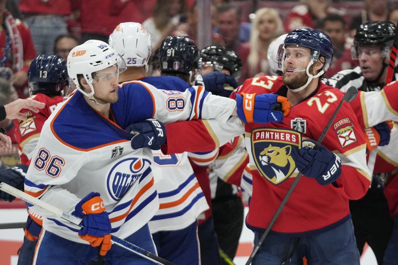 Florida Panthers center Carter Verhaeghe (23) and Edmonton Oilers defenseman Philip Broberg (86) grab each other during the second period of Game 5 of the NHL hockey Stanley Cup Finals, Tuesday, June 18, 2024, in Sunrise, Fla. (AP Photo/Wilfredo Lee)