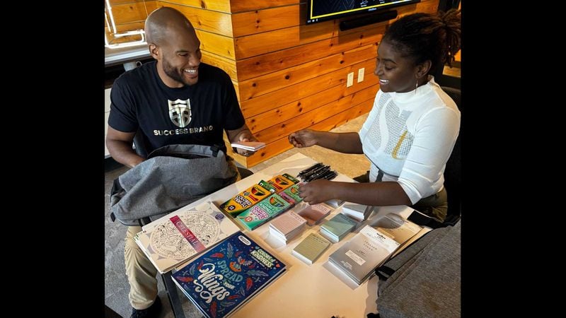 John Kennebrew, founder of mental health counseling provider Success Brand, works with volunteer Kela Taylor on supplies the organization is using in its outreach during 2024 Black gay pride activities in Atlanta.