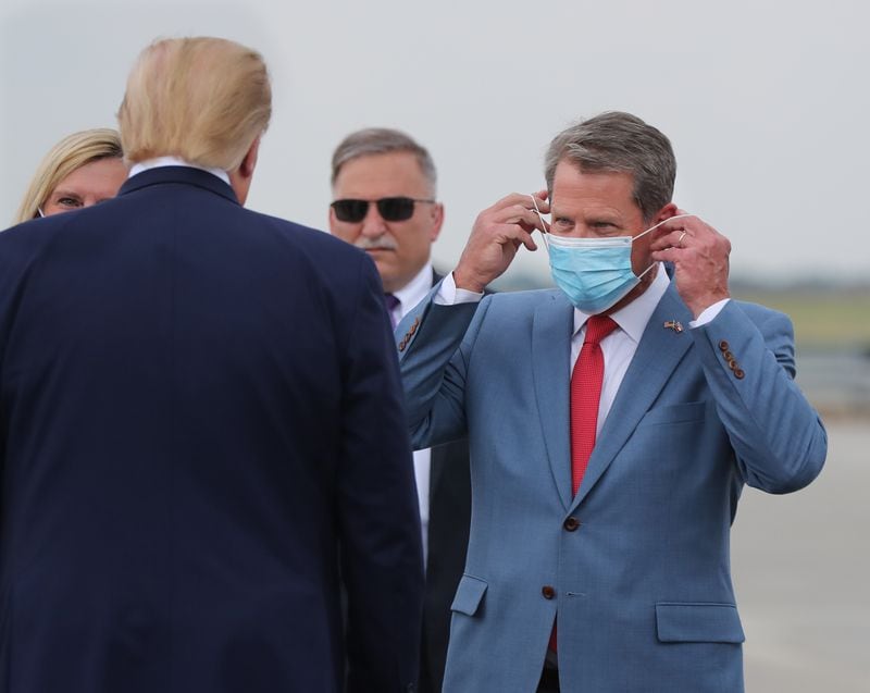 Kemp adjusts his face mask as he greets then-President Donald Trump at Hartsfield-Jackson International Airport in July 2020. Earlier that month, Kemp and  Toomey toured the state to promote wearing masks, albeit voluntarily. (Curtis Compton / ccompton@ajc.com)