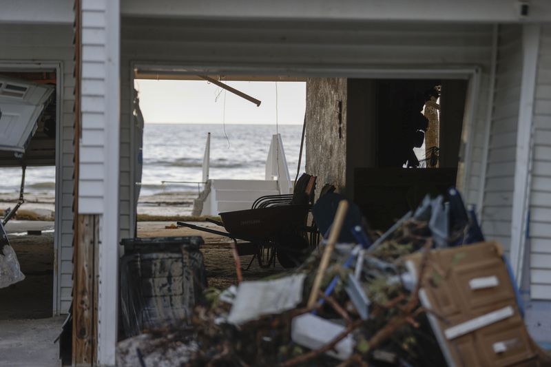 The sun shines through a hole in a building after storm surge from Hurricane Helene sent tons of sand into homes, Saturday, Sept. 28, 2024, in Madeira Beach, Fla. (Luis Santana/Tampa Bay Times via AP)