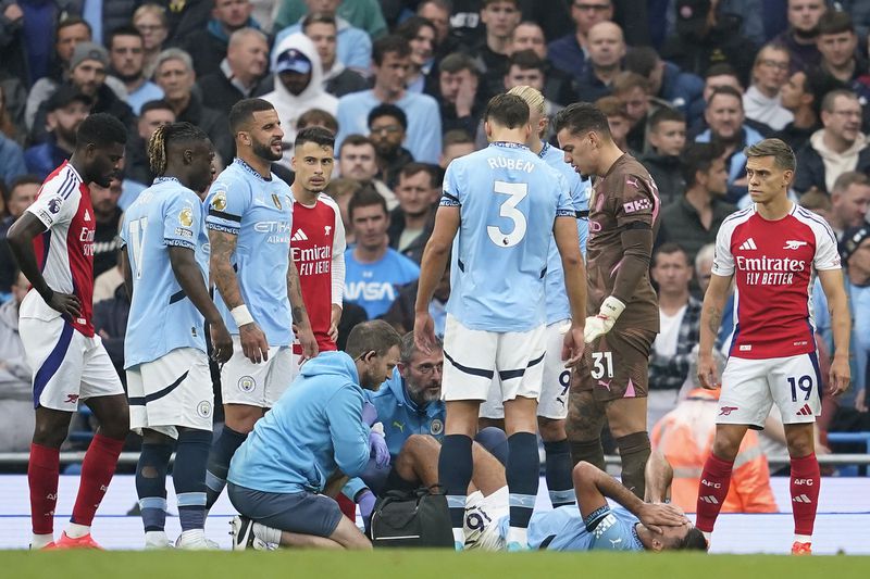 Manchester City's Rodri receives treatment during the English Premier League soccer match between Manchester City and Arsenal at the Etihad stadium in Manchester, England, Sunday, Sept. 22, 2024. (AP Photo/Dave Thompson)