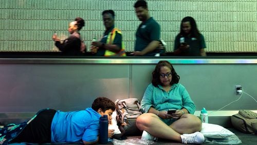 Monica Paz and Xavier Williams, 11, of Austin, Texas try to rest at the Atlanta airport Saturday night, following a global technology outage that has hampered airlines and other industries. (Arvin Temkar / AJC)