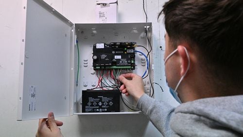 Ethan King, technician with Compass Security Solutions, checks the main alarm panel at a car dealership in Sandy Springs on Thursday, April 22, 2021. (Hyosub Shin / Hyosub.Shin@ajc.com)