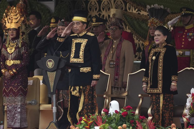 Indonesian President Joko Widodo, center, accompanied by his wife Iriana, right, salutes during a ceremony marking Indonesia's 79th anniversary of independence at the new presidential palace in its future capital city of Nusantara, still under construction on the island of Borneo, Thursday, Aug. 17, 2024. (AP Photo/Achmad Ibrahim)