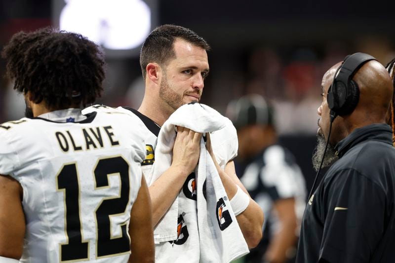 New Orleans Saints quarterback Derek Carr, center, speaks on the sidelines during the second half of an NFL football game against the Atlanta Falcons, Sunday, Sept. 29, 2024, in Atlanta. (AP Photo/Butch Dill)