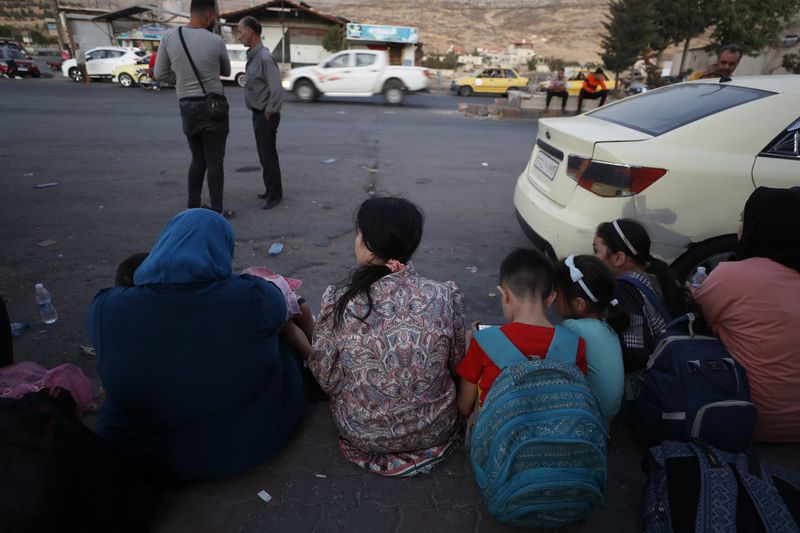 Lebanese fleeing the Israeli bombardment, sit on the ground as they arrive at the Syrian-Lebanese border crossing in Jdaidet Yabous, Syria, Tuesday, Sept. 24, 2024. (AP Photo/Omar Sanadiki)