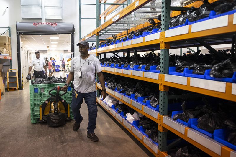 Warehouse Specialist David Callwood pulls a load of bagged, shelf-stable foods to be stored and used for next week's Meals on Wheels deliveries to clients, Friday, July 12, 2024, in Houston. (AP Photo/Annie Mulligan)