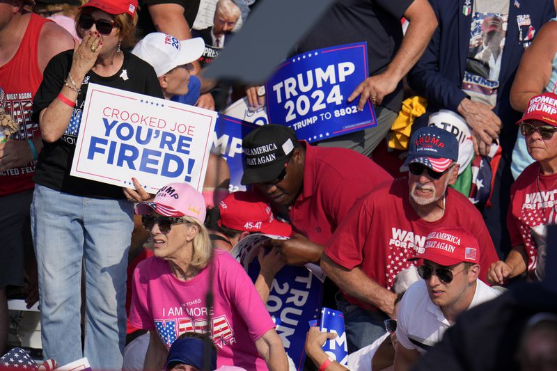 FILE - Members of the crowd react as U.S. Secret Service agents surround Republican presidential candidate former President Donald Trump at a campaign event in Butler, Pa., July 13, 2024. (AP Photo/Gene J. Puskar, File)