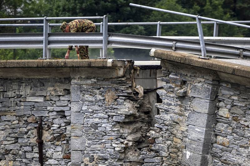 A member of the Swiss army measures the collapsed Visletto bridge between Visletto and Cevio, in the Maggia Valley, southern Switzerland on Sunday June 30, 2024. Authorities say weekend storms in Switzerland and northern Italy caused extensive flooding and landslides, leaving at least four people dead. Storms and heavy rain affected southern and western Switzerland on Saturday and overnight. (Michael Buholzer/Keystone via AP)