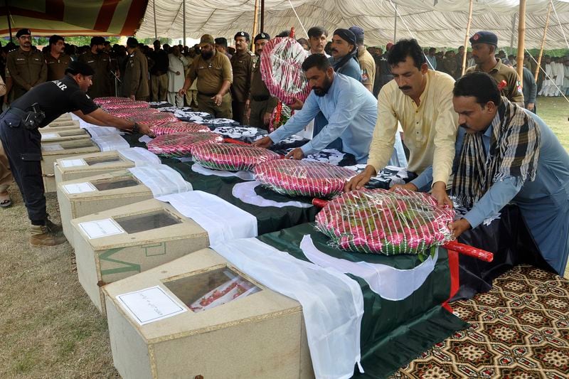 People place wreath on the caskets of police officers, who were killed in the gunmen ambushed on a police convoy in a deserted area, during a funeral prayer, in Rahim Yar Khan, Pakistan, Friday, Aug. 23, 2024. (AP Photo/Saddique Baloch)