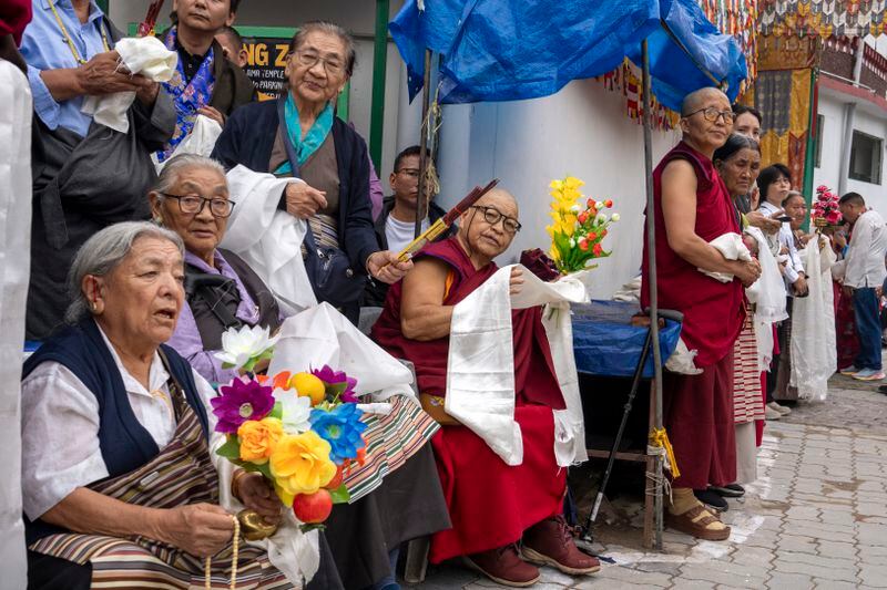 Exiled Tibetans wait with ceremonial scarves and flowers to welcome their spiritual leader the Dalai Lama before he arrived in Dharamshala, India, Wednesday, Aug. 28, 2024. (AP Photo/Ashwini Bhatia)