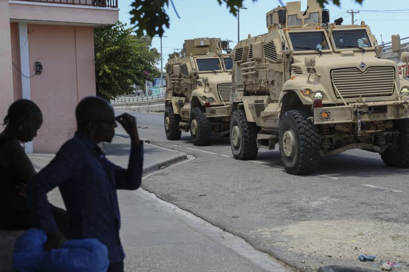 Kenyan police officers, part of a UN-backed multinational force, drive past residents in armored vehicles on the streets of Port-au-Prince, Haiti, Wednesday, Sept. 4, 2024. (AP Photo/Odelyn Joseph)