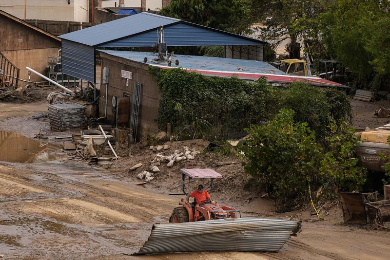 A worker moves debris in the aftermath of Hurricane Helene, Monday, Sept. 30, 2024, in Ashville, N.C. (AP Photo/Mike Stewart)