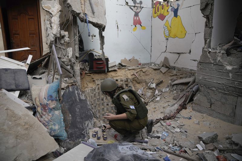 An Israeli soldier lights candles at the entrance of a tunnel where the military says six Israeli hostages were recently killed by Hamas militants in the southern Gaza Strip on Friday, Sept. 13, 2024. (AP Photo/Leo Correa)