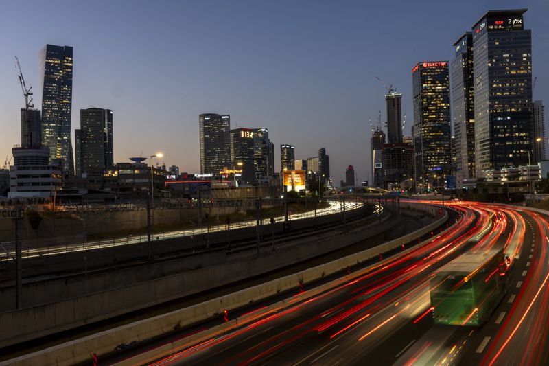 In this photo with a long exposure, traffic moves slowly in Tel Aviv, Israel, Wednesday, Aug. 14, 2024. Israel's economy is suffering from the nearly 11-month war with Hamas, as its leaders grind ahead with its offensive in Gaza that threatens to escalate into a wider conflict. (AP Photo/Ariel Schalit)