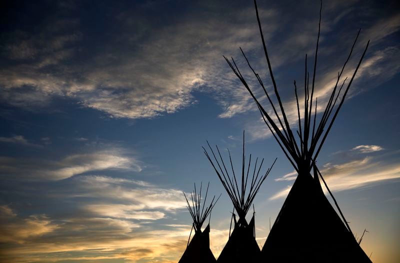 FILE - The sun sets during the North American Indian Days celebration on the Blackfeet Indian Reservation in Browning, Mont., on July 13, 2018. Many Native Americans thought a bitter debate over the U.S. capital’s football mascot was over when the team became the Washington Commanders. The original logo was designed by a member of the Blackfeet Nation. Now a white Republican U.S. senator from Montana is reviving the debate by blocking a bill funding the revitalization of the team's stadium unless the NFL and the Commanders bring back the former logo in some form. (AP Photo/David Goldman, File)