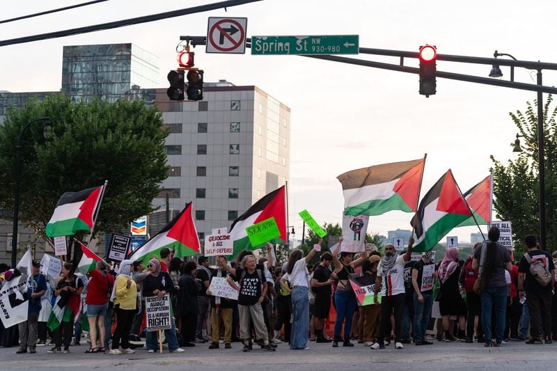 Protesters hold Palestinian flags at the intersection of 10th Street NW and Spring Street NW in Atlanta on Thursday, June 27, 2024. Nearby, President Joe Biden and former President Donald Trump participated in a debate hosted by CNN. (Seeger Gray / AJC)