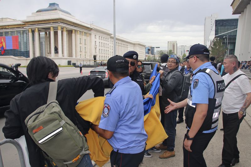 Police and security officers prevent members of the "No War" group from holding up a Ukrainian flag during the visit of Russian President Vladimir Putin in Ulaanbaatar, Mongolia, Tuesday, Sept. 3, 2024. (AP Photo/Ganbat Namjilsangarav)