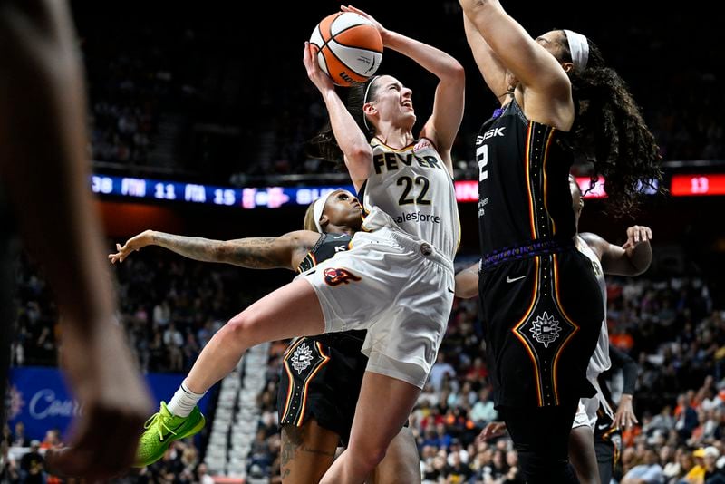 Indiana Fever guard Caitlin Clark (22) is fouled from behind by Connecticut Sun guard Tiffany Mitchell (3) as she drives against forward Brionna Jones (42) during the fourth quarter of a WNBA basketball game, Tuesday, May 14, 2024, in Uncasville, Conn. (AP Photo/Jessica Hill)