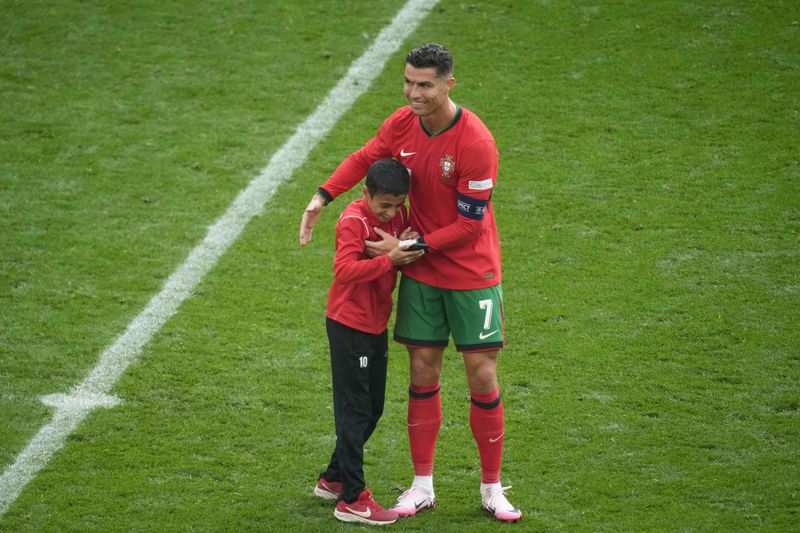 Portugal's Cristiano Ronaldo embraces a young pitch invader during a Group F match between Turkey and Portugal at the Euro 2024 soccer tournament in Dortmund, Germany, Saturday, June 22, 2024. (AP Photo/Michael Probst)