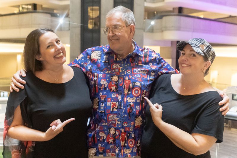 DragonCon Co-Founder Pat Henry poses for a portrait alongside his daughters Rachel Reeves, left, and Mandy Collier, right, at Atlanta Marriott Marquis on Wednesday, July 26, 2023 in Atlanta. The sisters will be taking the mantle from their father. (Michael Blackshire/Michael.blackshire@ajc.com)

