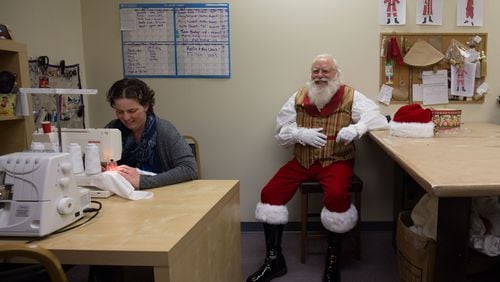 Louis Knezevich, dressed as Santa Claus, sits as Brittany Johnson sews a mock up collar for a Mrs. Claus suit, at J&R Santaprises. BRANDEN CAMP/SPECIAL