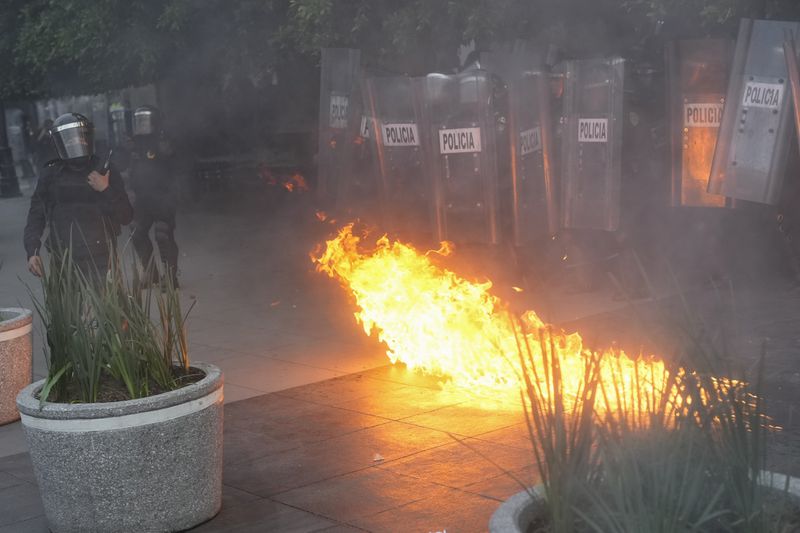 A fire breaks out during a march to mark the 56th anniversary of the killing of student protesters at Tlatelolco plaza when soldiers opened fire on a peaceful demonstration, in Mexico City, Wednesday, Oct. 2. 2024. (AP Photo/Eduardo Verdugo)