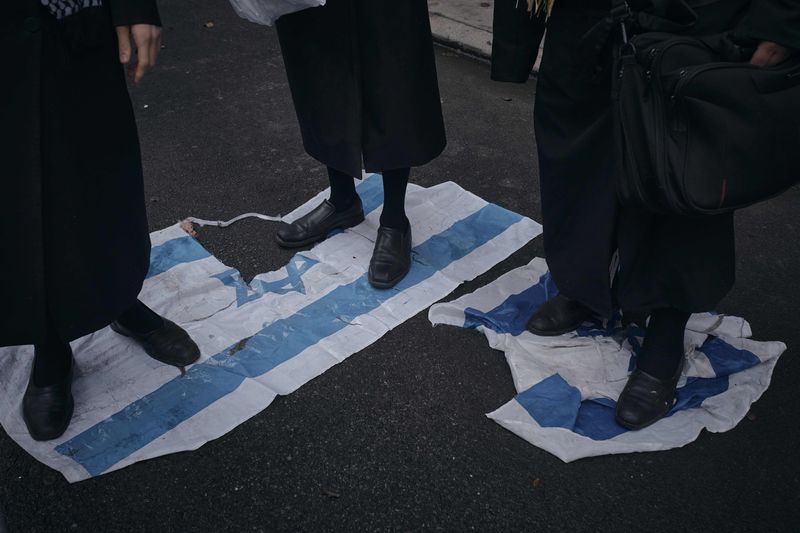 Haredi Jews step on the Israeli flag to protest against Prime Minister of Israel Benjamin Netanyahu in front of his hotel during the 79th session of the United Nations General Assembly, in New York, on Friday, Sept. 27, 2024. (AP Photo/Andres Kudacki)