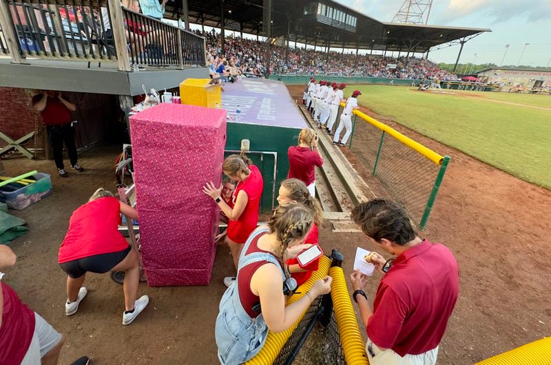 Members of the Macon Bacon's "Sizzle Squad" prepare to unveil mascot "Kevin Bacon," who made his grand entrance wrapped as a gift at last weekend's home opener at Luther Williams Field. (Joe Kovac Jr. / AJC)