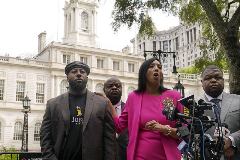 Shamel Kelly, left, with his attorneys Bernarda Villalona, center, and Harry Daniels, right, hold a news conference in New York's City Hall Park, Tuesday, Oct. 1, 2024. (AP Photo/Richard Drew)