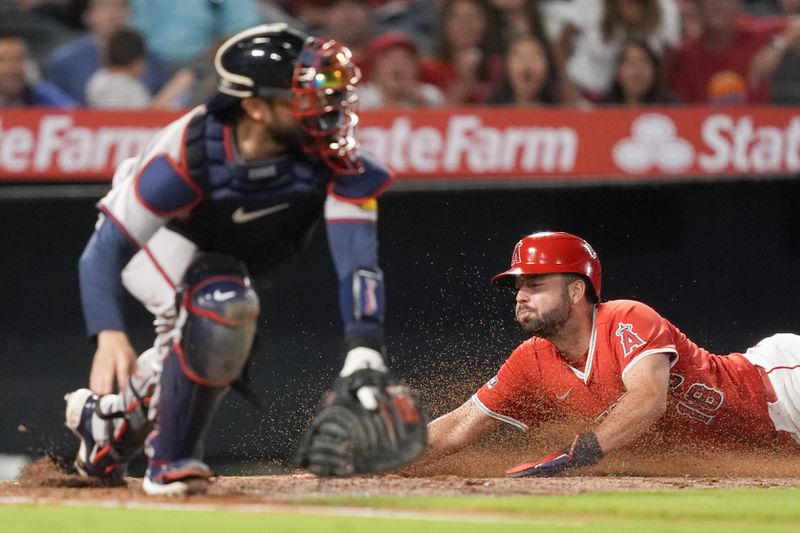 Los Angeles Angels' Nolan Schanuel, right, slides home past Atlanta Braves catcher Travis d'Arnaud, left, to score off a double by Kevin Pillar during the sixth inning of a baseball game, Saturday, Aug. 17, 2024, in Anaheim, Calif. (AP Photo/Ryan Sun)