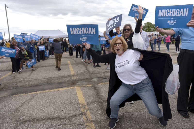 Supporters of Democratic presidential nominee Vice President Kamala Harris, including Carrie Charlick in the white shirt at right, cheer with members of the Harris campaign staff as they line up to enter the Dort Financial Center for a rally in Flint, Mich., Friday, Oct. 4, 2024. (AP Photo/Carolyn Kaster)