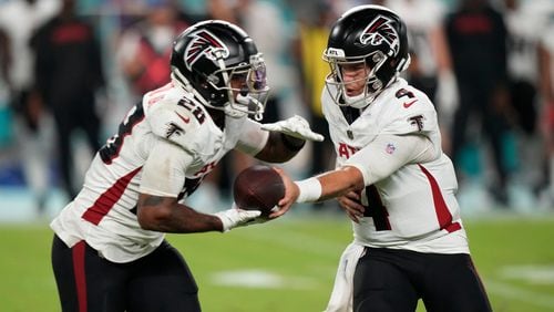 Atlanta Falcons quarterback Taylor Heinicke (4) hands the ball to running back Carlos Washington Jr. (28) during the second half of a pre season NFL football game against the Miami Dolphins, Friday, Aug. 9, 2024, in Miami Gardens, Fla. (AP Photo/Wilfredo Lee)