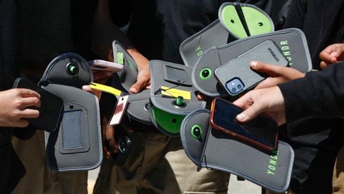 FILE - A student uses their cell phone after unlocking the pouch that secures it from use during the school day at Bayside Academy, Aug. 16, 2024, in San Mateo, Calif. (Lea Suzuki/San Francisco Chronicle via AP, File)