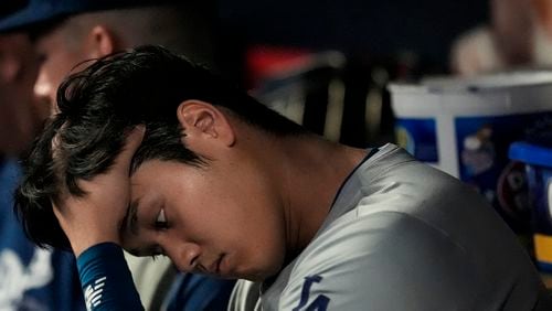 Los Angeles Dodgers two-way player Shohei Ohtani sits in the dugout in the sixth inning of a baseball game against the Atlanta Braves, Friday, Sept. 13, 2024, in Atlanta. (AP Photo/Mike Stewart)