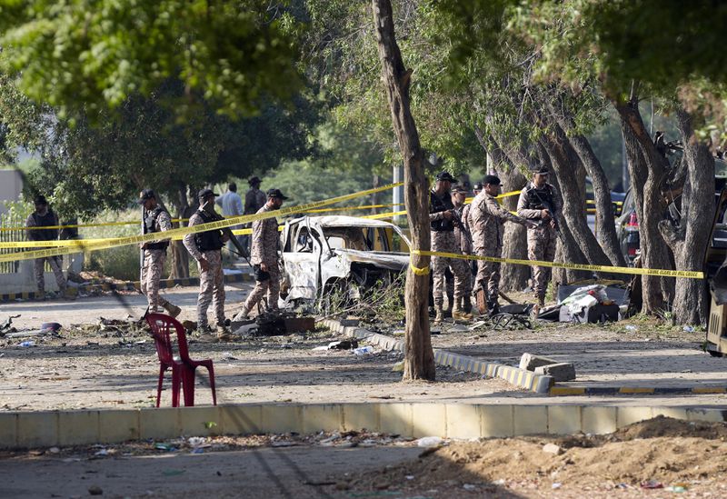 Security officials work on the site of an explosion that caused injures and destroyed vehicles outside the Karachi airport, Pakistan, Monday, Oct. 7, 2024. Pakistani Baloch separatists claim deadly bomb attack that killed 2 Chinese near Karachi airport. (AP Photo/Fareed Khan)