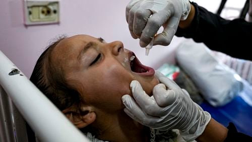 A health worker administers a polio vaccine to a child at a hospital in Khan Younis, Saturday, Aug. 31, 2024. (AP Photo/Abdel Kareem Hana)