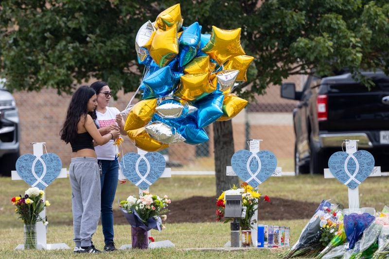 Mourners visit crosses erected at Apalachee High School on Friday, Sept. 6, 2024, in Winder, Ga. A 14-year-old Apalachee student is accused of shooting and killing two fellow students and two teachers and injuring nine others at Apalachee High School on Wednesday. (Arvin Temkar / AJC)