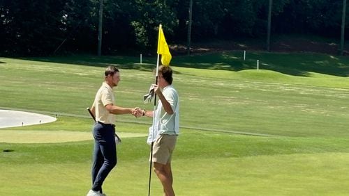 Garrett Engle (L) accepts congratulations from his opponent's caddie after tapping in on the 18th hole Engle, who plays at Tennessee-Chattanooga, won by shots at Druid Hills Golf Club, June 8, 2024.