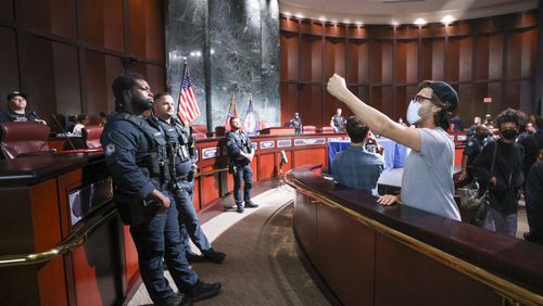 Protestors yell at council members as Atlanta Police officers protect the Atlanta City Council chambers after the council voted 11 to 4 to approve legislation to fund the training center, on Tuesday, June 6, 2023, in Atlanta. (Jason Getz / Jason.Getz@ajc.com)