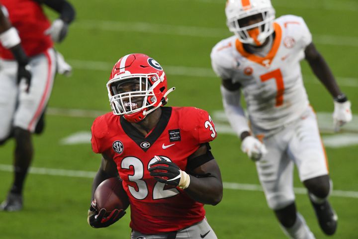Georgia linebacker Monty Rice (32) runs for a TD as Tennessee wide receiver Brandon Johnson (7) after Rice recovered a fumble which he caused during the second half of a football game on Saturday, Oct. 10, 2020, at Sanford Stadium in Athens. Georgia won 44-21. JOHN AMIS FOR THE ATLANTA JOURNAL- CONSTITUTION