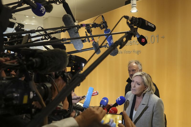 French far-right leader Marine Le Pen, front, speaks to the media as she arrives at the court house in Paris, Monday, Sept. 30, 2024. (AP Photo/Thibault Camus)