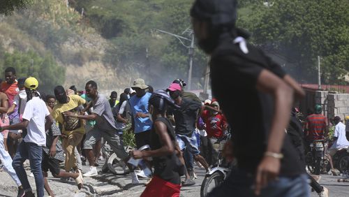 People run from tear gas fired by police to disperse protesters demanding police and the Prime Minister take immediate action against gangs in Port-au-Prince, Haiti, Monday, Aug. 19, 2024. (AP Photo/Odelyn Joseph)